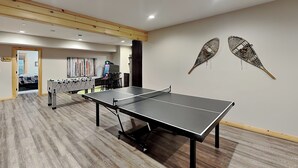 Um quarto com mesa de pingue-pongue, mesa de futebol de mesa e dois objetos decorativos fixados na parede.