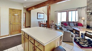 A spacious living area with a large wooden dining table, a sofa, and a kitchen island.