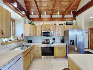 Cocina con gabinetes de madera, refrigerador de acero inoxidable, microondas y lavavajillas.