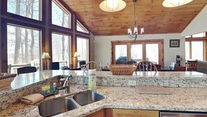 A spacious kitchen with granite countertops, wooden cabinets, and a large island with a sink. - One Ski Hill by Taylor Made Deep Creek (McHenry)