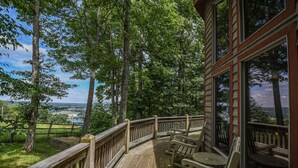 A wooden deck with a view of a lake and trees. - One Ski Hill by Taylor Made Deep Creek (McHenry)