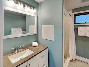 A bathroom with a sink, mirror, and shower.