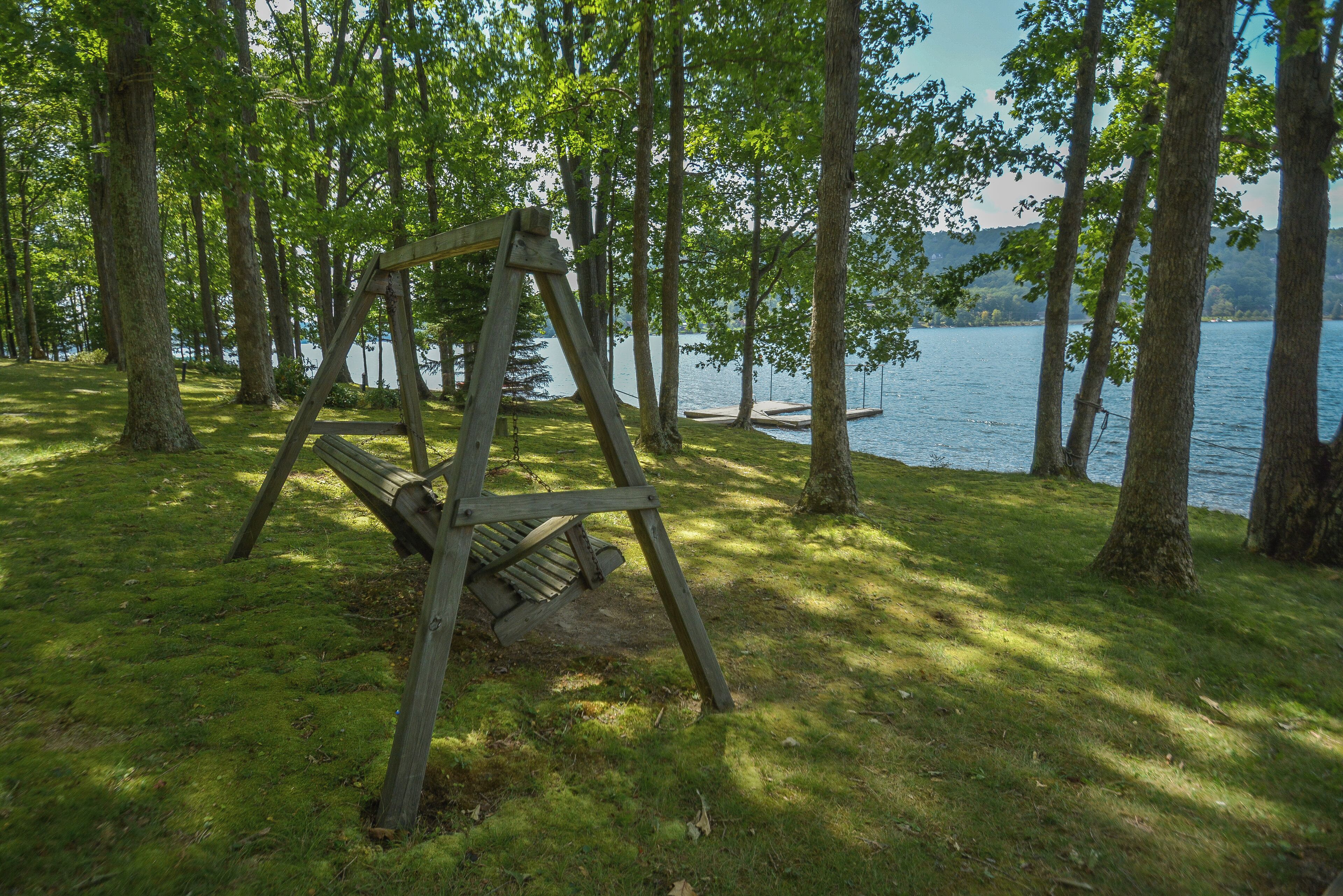 Puinen keinuteline nurmialueella, taustalla puita ja järvi.