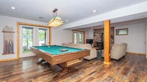 Une table de billard dans une pièce dotée d’un plancher en bois et d’un mur décoratif en pierre.