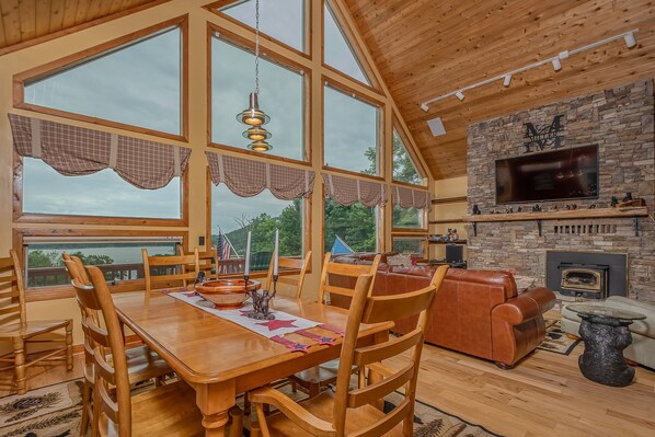 Relax in this inviting living area with a high ceiling, large windows, and a stone fireplace.