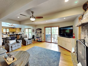 A spacious living room with a fireplace, a television, and a large window. - Picture Perfect by Taylor Made Deep Creek (Oakland)
