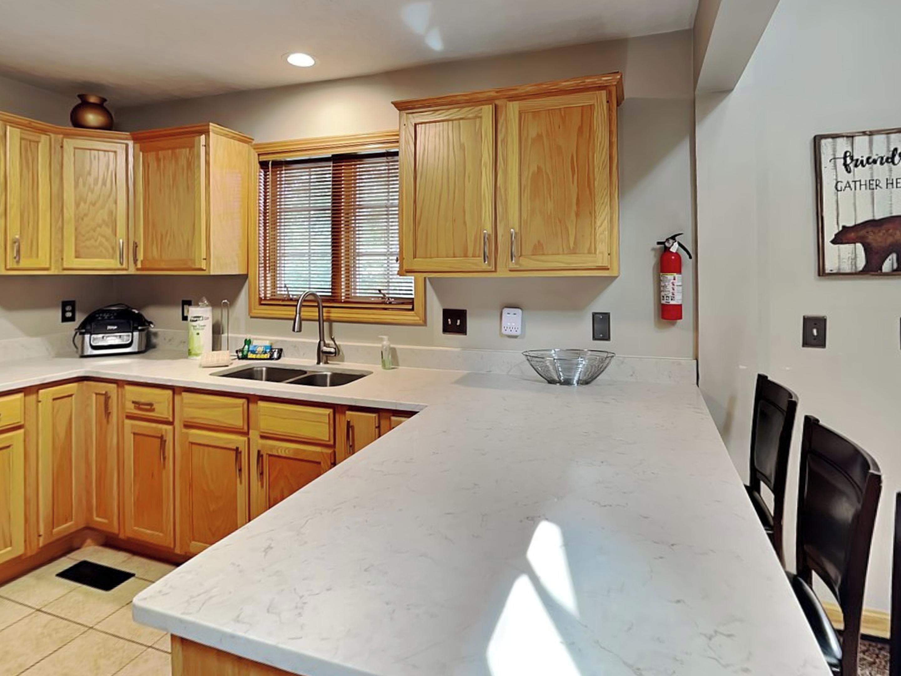 A kitchen with wooden cabinets, a marble countertop, a sink, and a fire extinguisher.