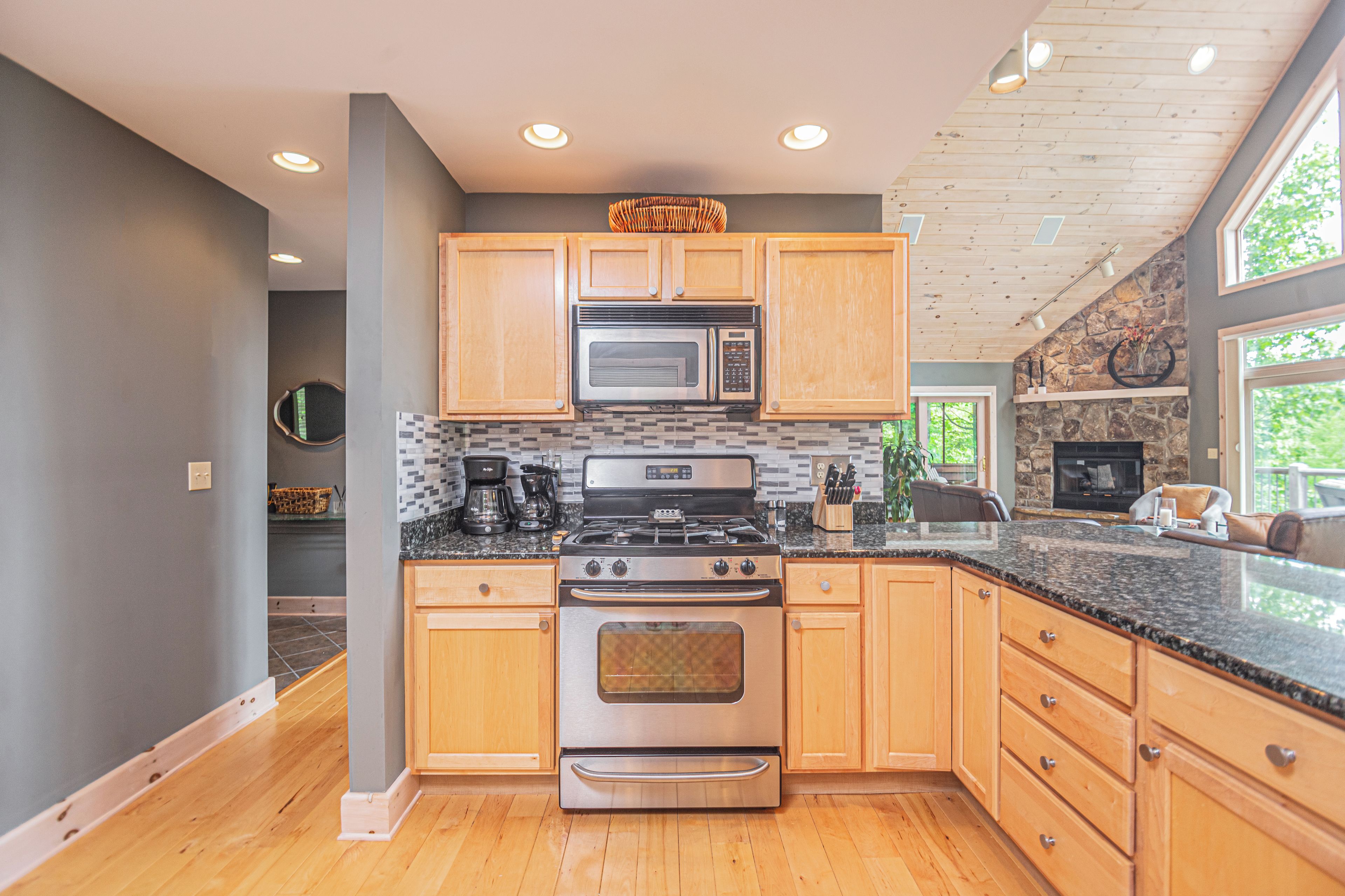 A modern kitchen with wooden cabinets, a stainless steel stove, and a stone accent wall.