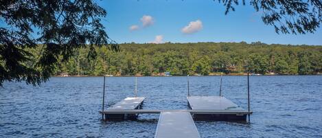 A wooden dock extending into a calm lake, surrounded by dense forest.