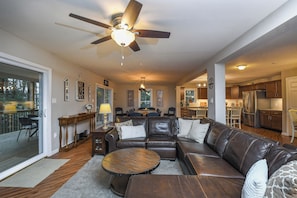 A spacious living room with a leather sofa, a round coffee table, and a ceiling fan.