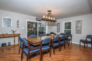 A dining room with a large wooden table, blue upholstered chairs, and a chandelier.