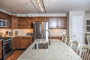 A kitchen with wooden cabinets, stainless steel appliances, a granite countertop, and a built-in sink. - Putter Place by Taylor Made Deep Creek (Oakland)