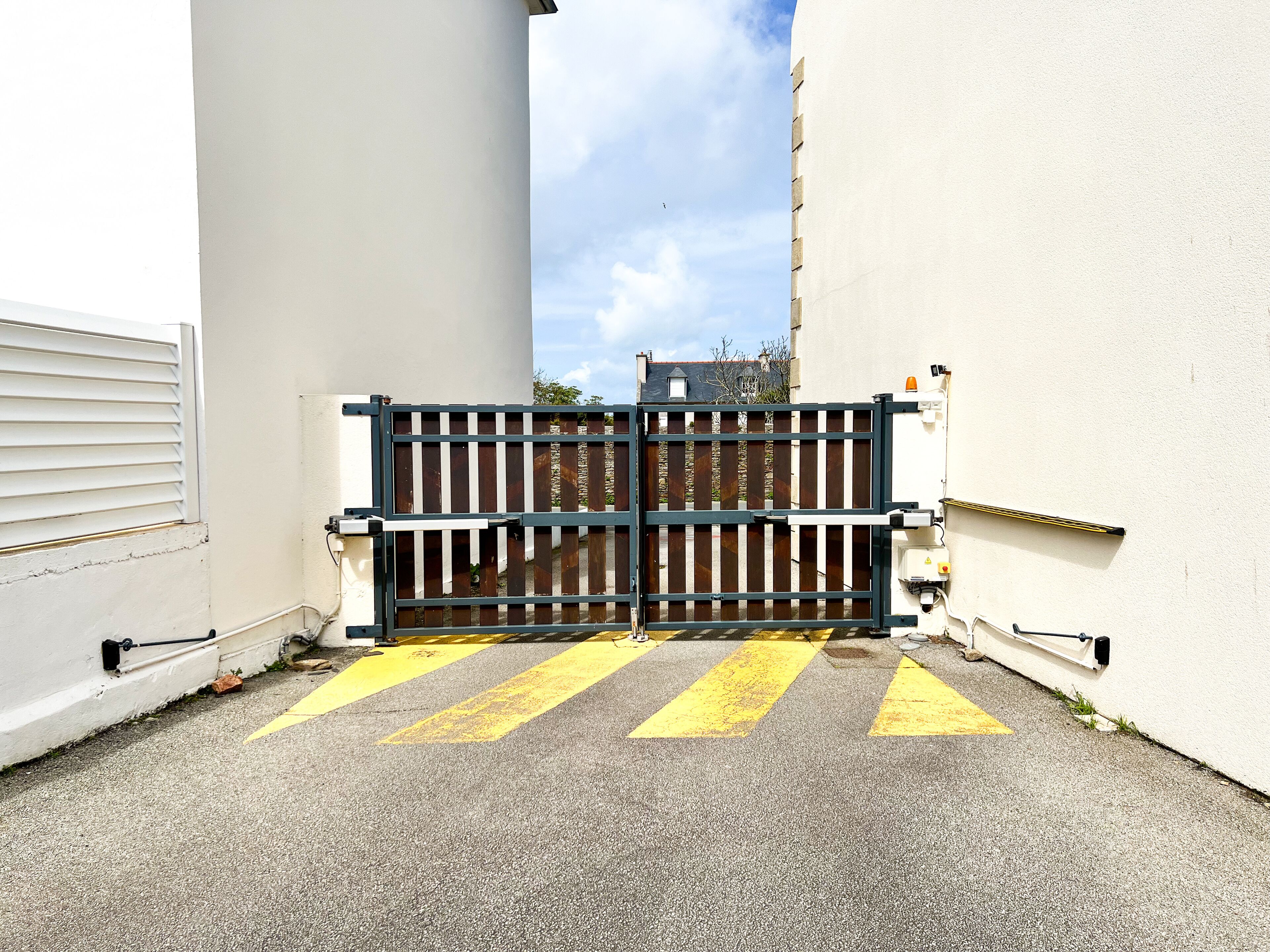 Una entrada tancada amb una porta, un pas de zebra groc i un edifici blanc amb una finestra i una porta.