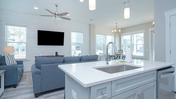 A modern kitchen with a central island, a built-in dishwasher, and a large window providing natural light. - Sandy of Panama City Beach - Ocean View, Heated Pool, Steps to Beach, Sleeps 18 (Panama City Beach)