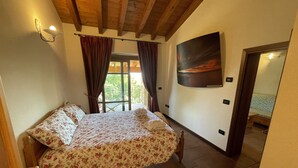 Un dormitorio con cama, ventana con cortinas, una lámpara de pared y un cuadro.
