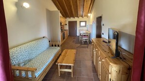 Un interior acogedor con un banco de madera, una mesita y un televisor sobre un mueble de madera.