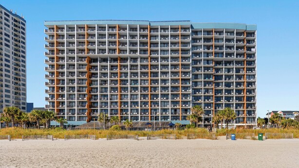 Un hotel de varios pisos con balcones, cerca de la playa.