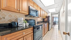 Una cocina con armarios de madera, microondas, cafetera y estufa.