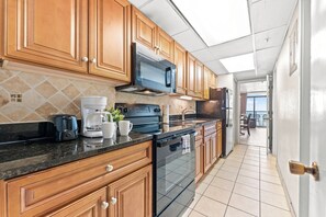 A kitchen with wooden cabinets, a microwave, a stove, and a refrigerator.