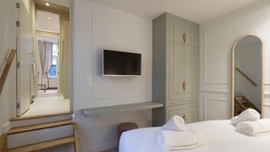 Et hotelværelse med seng, fjernsyn monteret på væggen, et garderobeskab og et spejl.