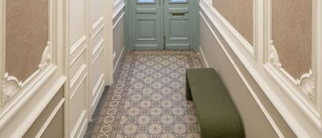 Un pasillo con una puerta azul, un piso estampado y un banco.