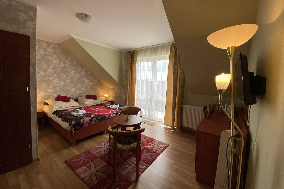 Ein Schlafzimmer mit Bett, Stuhl, Tisch und Lampe.