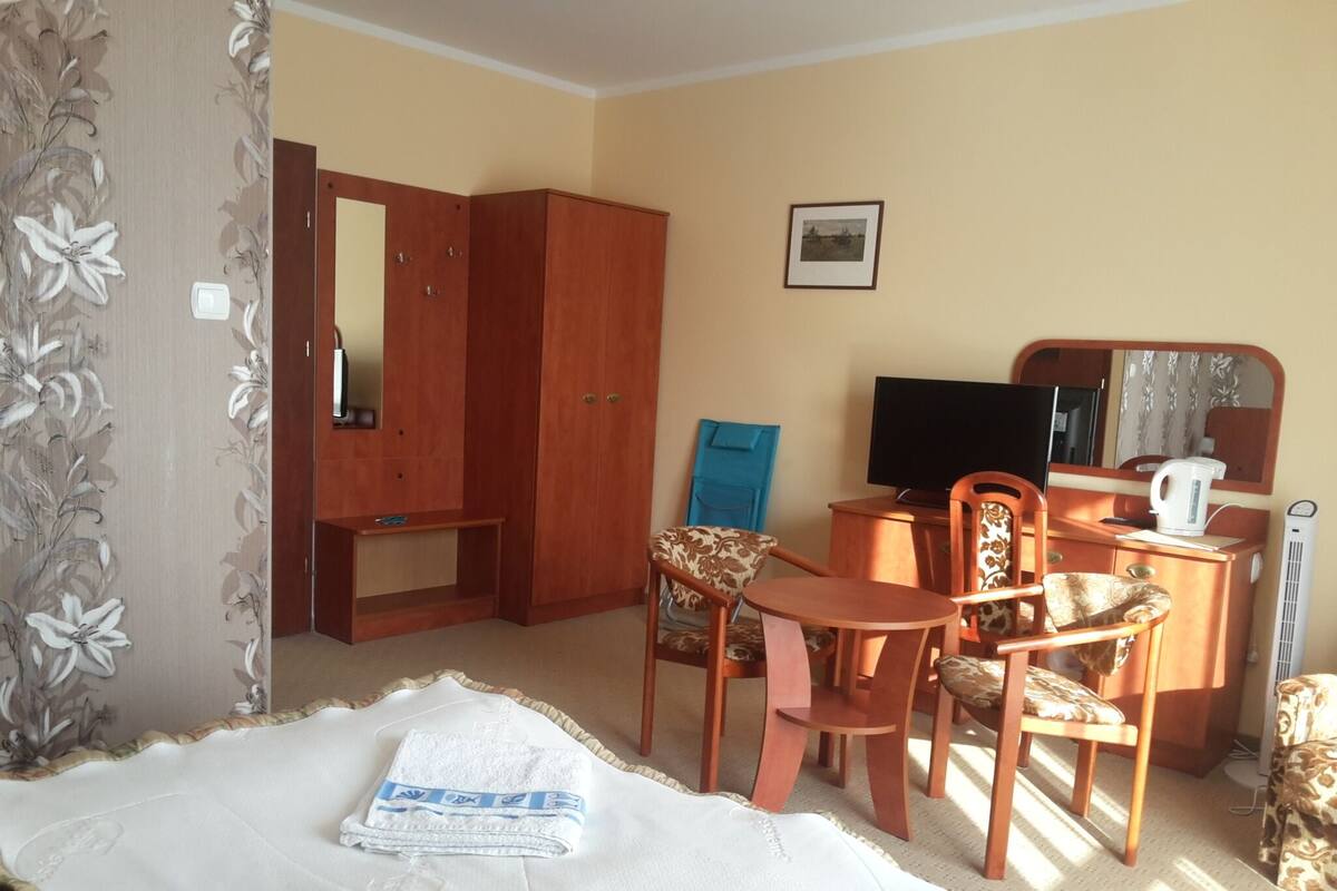 Ein Hotelzimmer mit Bett, Schreibtisch mit Stuhl, Fernseher, Spiegel und Kleiderschrank.