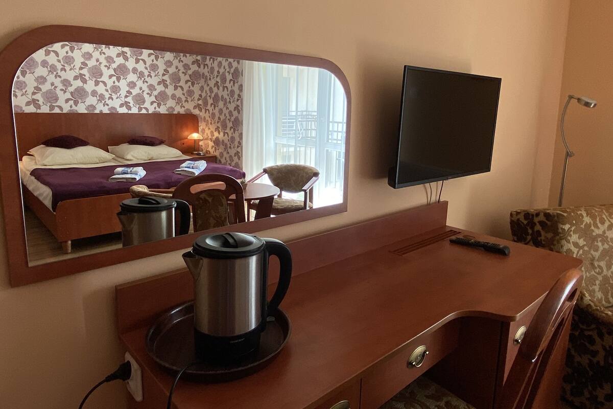 Ein Hotelzimmer mit einem Bett, einem Schreibtisch mit Kaffeemaschine, einem Sessel, einem Fernseher und einem Fenster mit Blick.