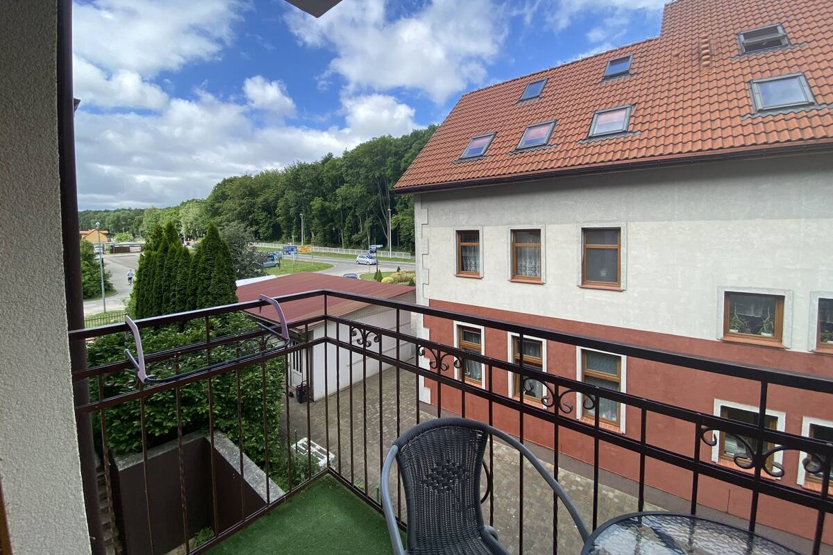 Ein Balkon mit Blick auf ein Gebäude mit roten Ziegeldächern und zahlreichen Fenstern.