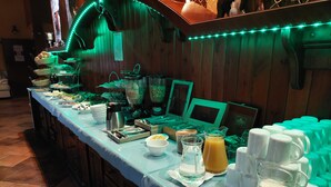 Montaje de bufé con diversos alimentos y bebidas, que incluye una estación de café y un dispensador de zumo.
