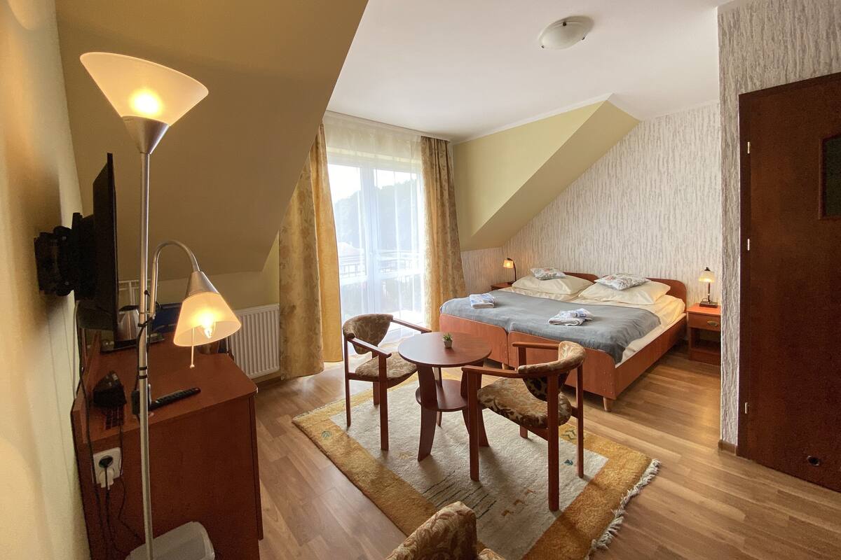 Ein Schlafzimmer mit Bett, Schreibtisch, Stuhl, Lampe und Fernseher.
