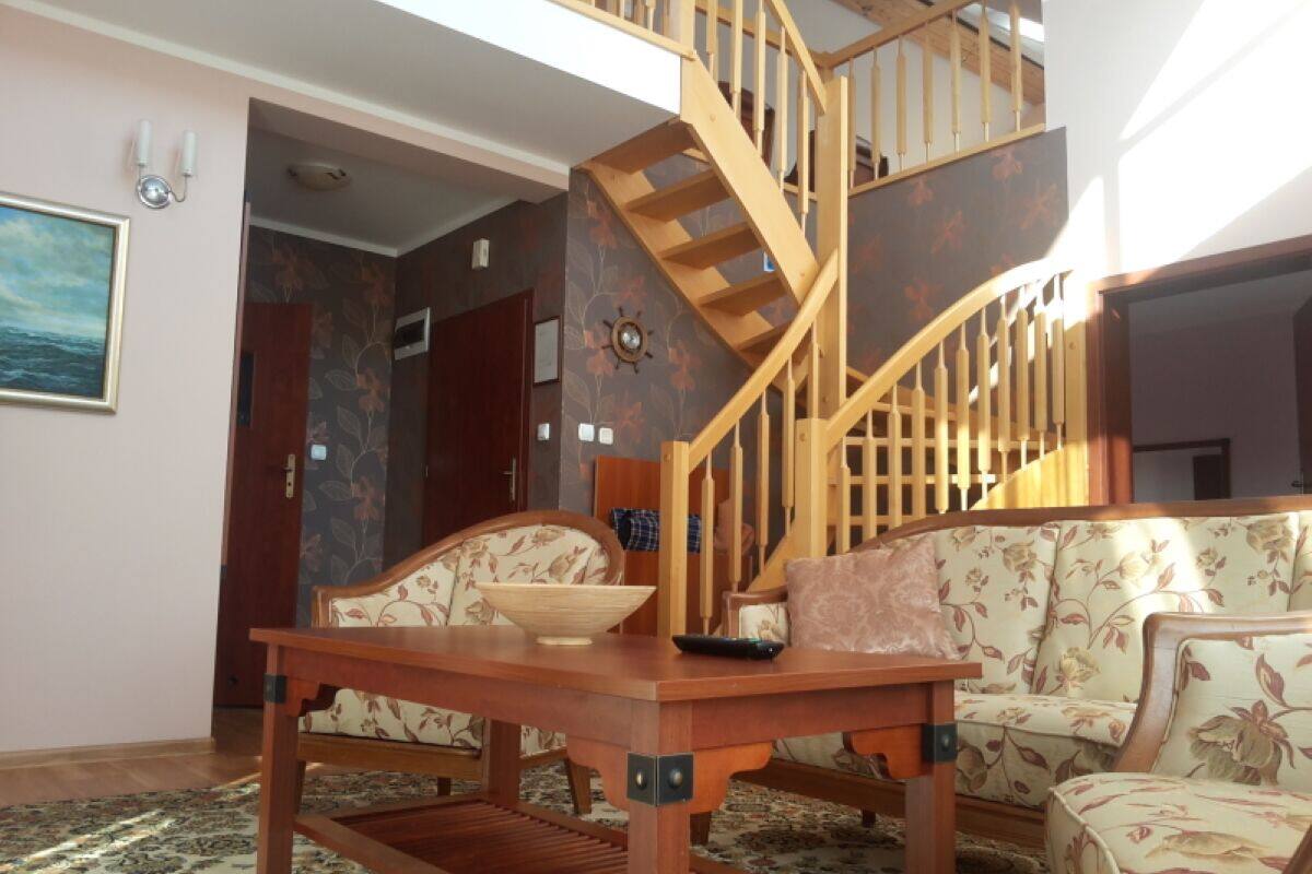 Ein Wohnzimmer mit einer Holztreppe, einem Sofa, einem Couchtisch und einer Schale.