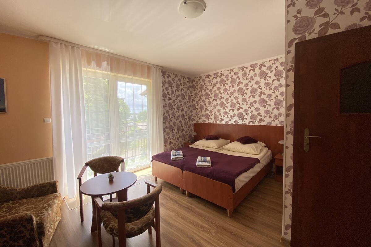 Ein Schlafzimmer mit einem Bett, einem Sessel, einem Tisch und einer Tür.