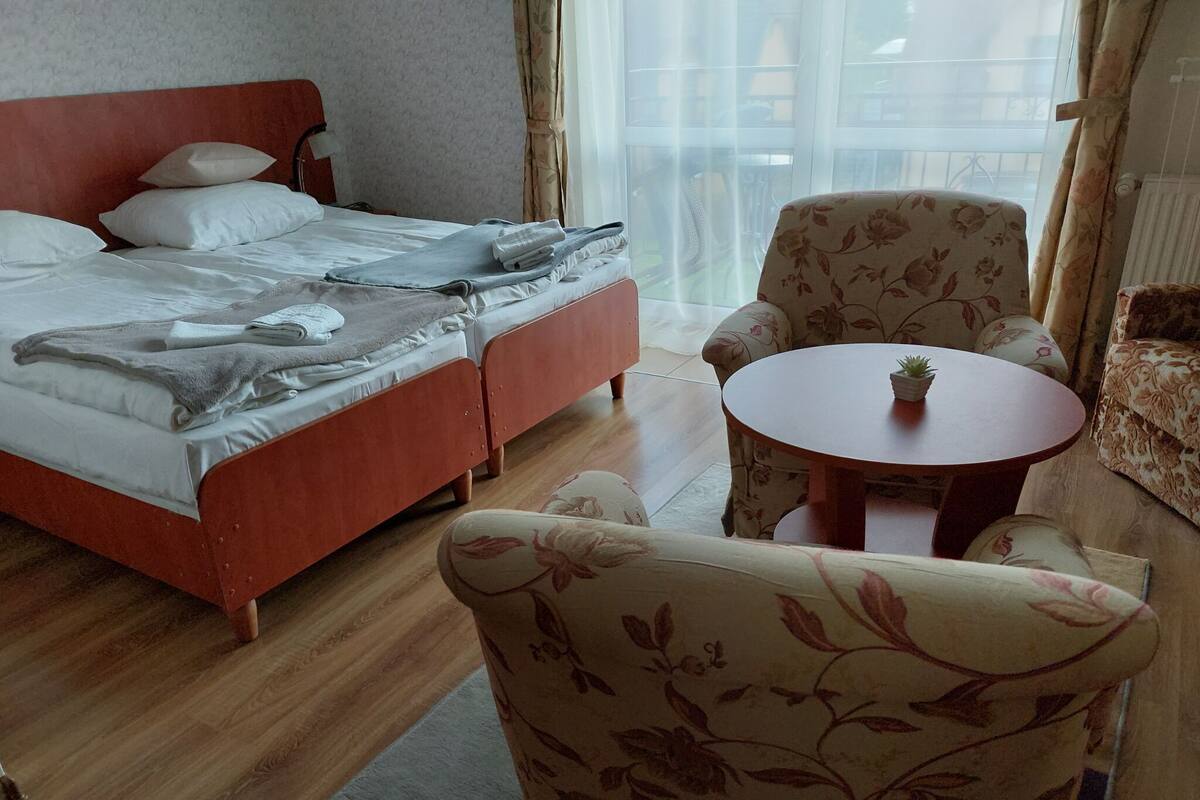 Ein Hotelzimmer mit einem Bett, einem runden Tisch mit einer Pflanze und floralen Ohrensesseln.