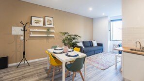 A modern apartment with a dining area, a sofa, a kitchen, and a coat rack.