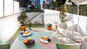 A rooftop terrace with a table set for two, featuring a glass bowl of fruit, a plate of pastries, and wine glasses. - WALAA Home@Almada Terrace by LovelyStay (Porto)