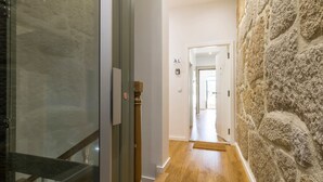 A hallway with a glass door, a wooden door, and a stone wall. - WALAA Home@Almada Terrace by LovelyStay (Porto)