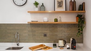 A modern kitchen with a herringbone tile backsplash, a stainless steel sink, wooden shelves, and a coffee maker. - WALAA Home@Almada Terrace by LovelyStay (Porto)
