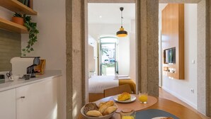 A modern hotel room with a kitchenette, breakfast table, and a bed with a view of the outside. - WALAA Home@Almada Terrace by LovelyStay (Porto)