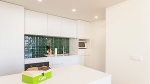 Una cucina moderna con mobili bianchi, zoccolo a mosaico verde e forno a microonde.