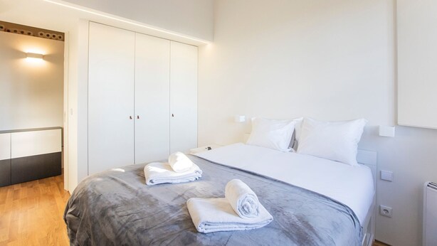 Una camera d'albergo con un letto, un armadio e un comodino.