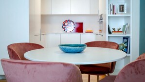 Et moderne spiseområde med et rundt bord, pink stole og en blå skål.