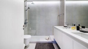 Ein modernes Badezimmer mit einer gläsernen Dusche, einer weißen Toilette und einem Waschtisch mit Spiegel.
