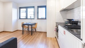 Et moderne køkken med hvide skabe, en sort bordplade og et spiseområde med bord og stole.