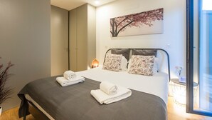 A modern bedroom with a large bed, a nightstand, a bedside table, and a window with a view. - Downtown Studio w/ AC & Patio by LovelyStay (Porto)