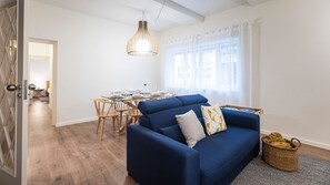 Una sala de estar moderna con un sofá azul, una mesa de comedor y una lámpara colgante.