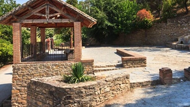 A stone structure with a roof, surrounded by a stone wall and a paved area. - Cottage (Tózar)