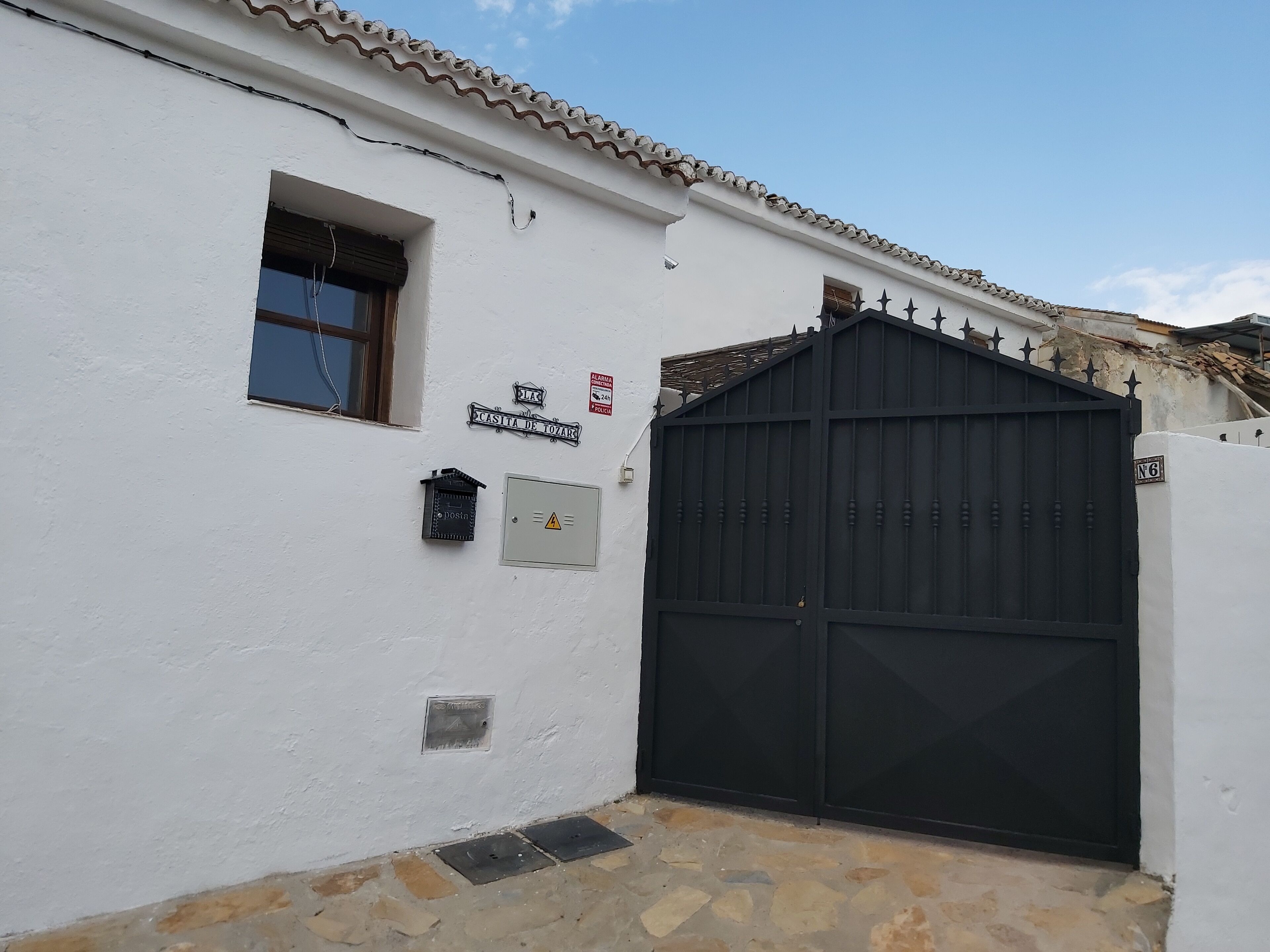 Un bâtiment blanc avec une porte noire, une fenêtre et une boîte aux lettres.