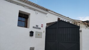 A white building with a black gate, a window, and a mailbox. - Cottage (Tózar)