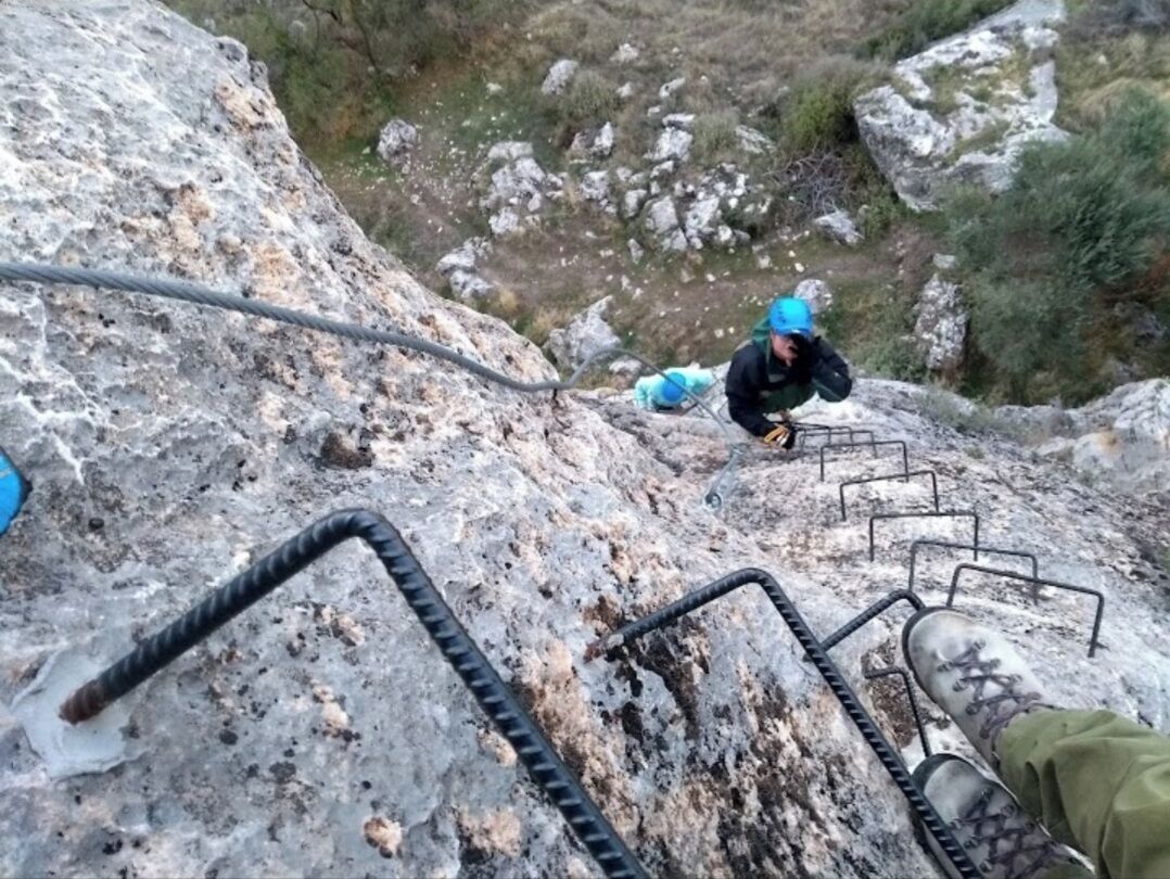 Une personne qui monte un escalier extérieur en pierre, doté de rampes métalliques.